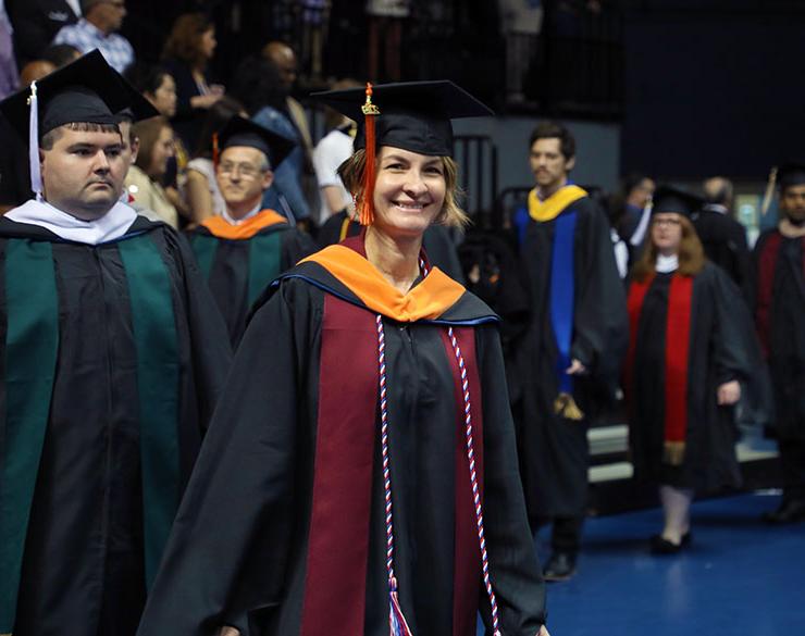 Woman smiles in her cap and gown at commencement